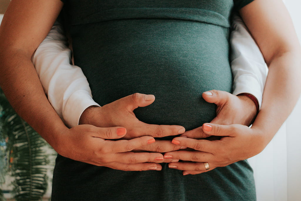 Coppia che abbraccia il pancione in attesa di un bambino